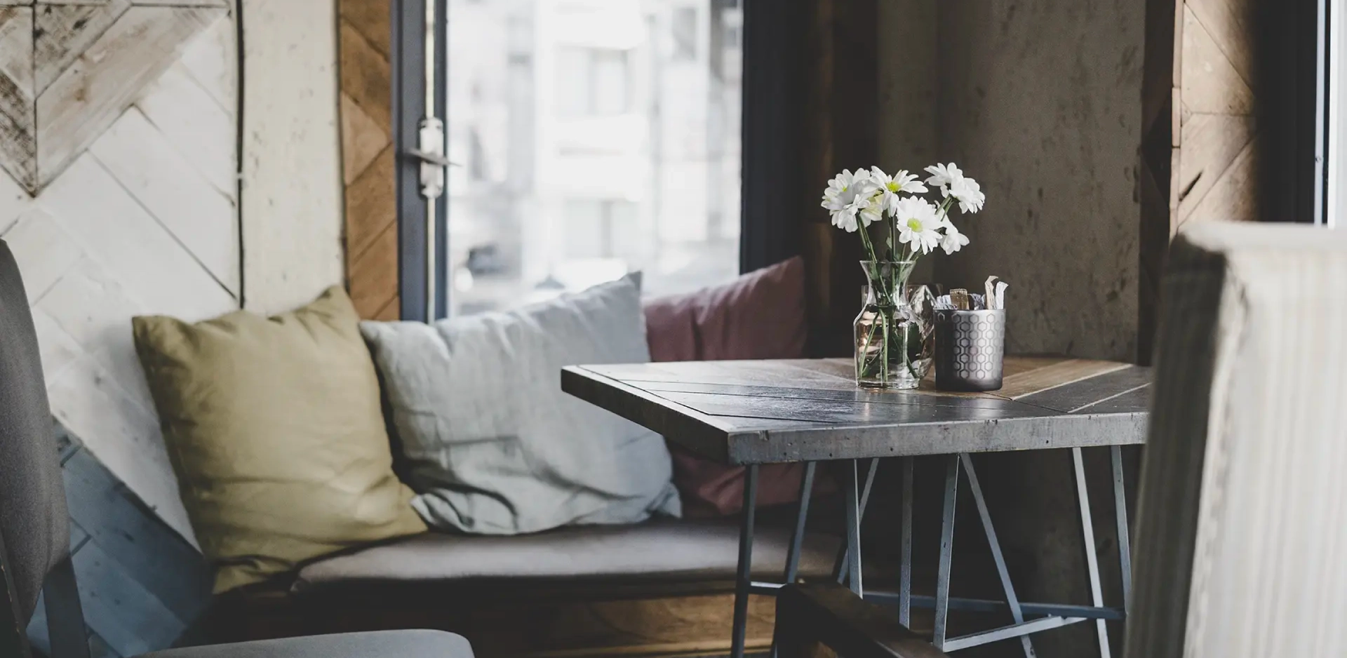 Cozy cafe corner with flowers and pillows.