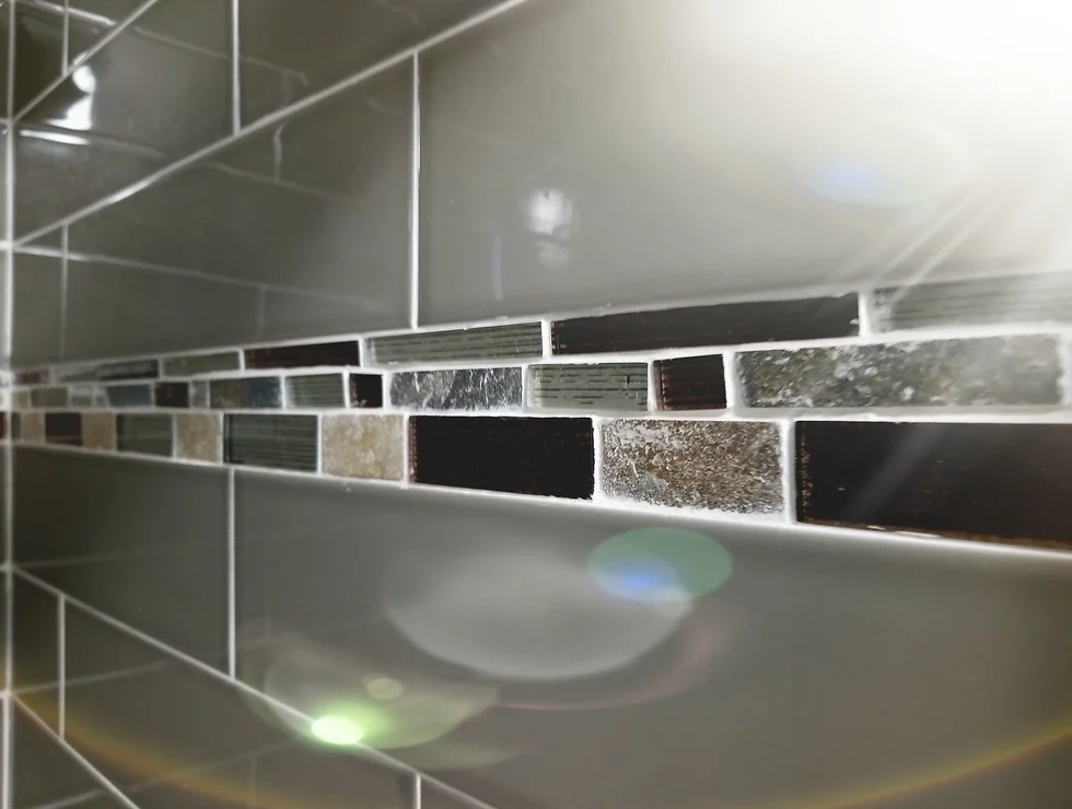 Gray tile wall with mosaic accent.