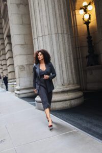 A woman walking down the street in front of a building.